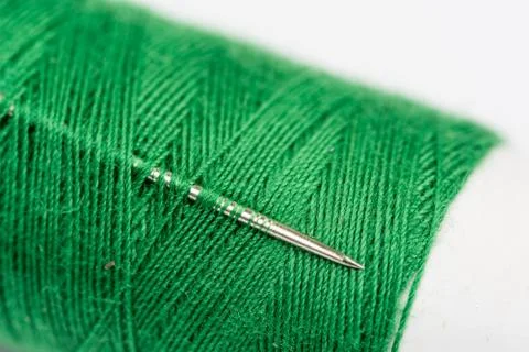 Needle head on the green thread over white background Foto stock