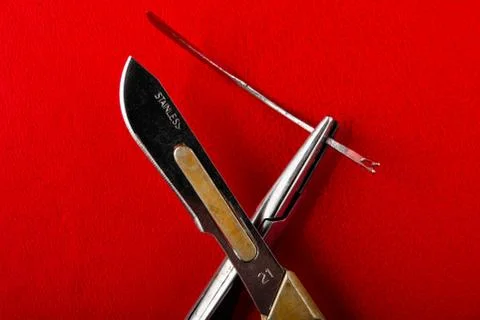 Needle in the needle holder scalpel on a red background Stock Photos