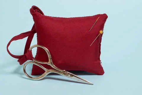 A needle pad and scissors on a blue background Stock Photos