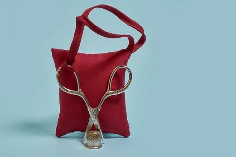 A needle pad, scissors and a thimble on a blue background Stock Photos