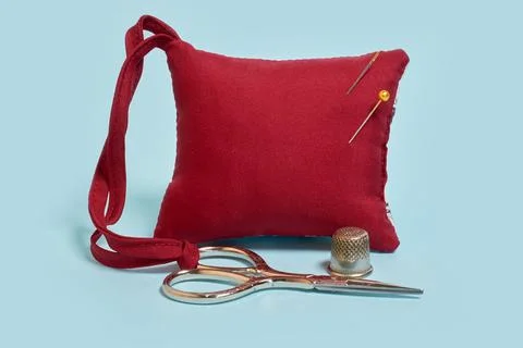 A needle pad, scissors and a thimble on a blue background Stock Photos