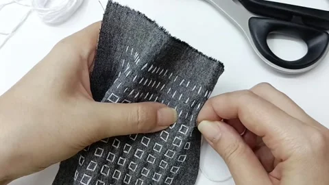 Needle pulling thread through fabric embroidery detail Video stock 330050582