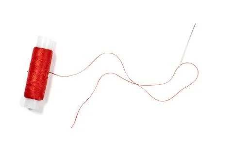 Needle with red thread and spool of thread on a white background Stock Photos