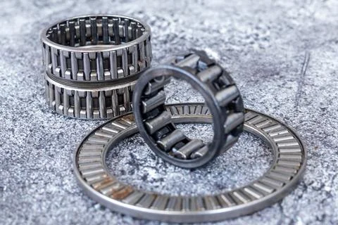 Needle roller bearings and thrust bearing cage assemblies lying on concrete.. Stock-Fotos