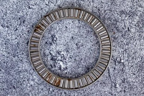 Needle roller thrust bearing cage assembly lying on concrete workshop floor. Stock Photos