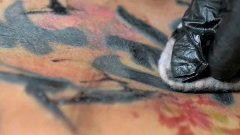Needle tattoo machine injects ink into the skin of a girl. Tattoo artist puts a Video stock 129992902
