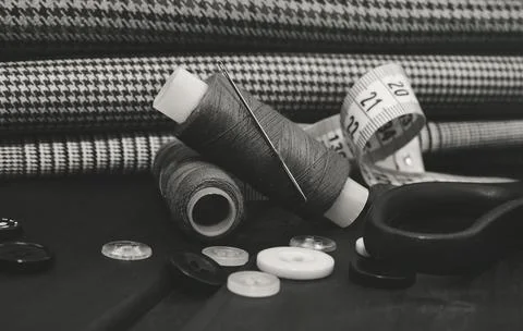 A needle with thread, buttons and scissors lie on a wooden background. Stock Photos