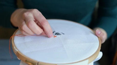A needle with a thread create a pattern on the canvas in the hands of a girl Stock Footage 129849283
