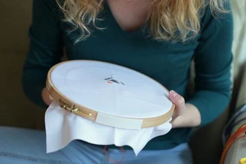 A needle with a thread create a pattern on the canvas in the hands of a girl Foto stock