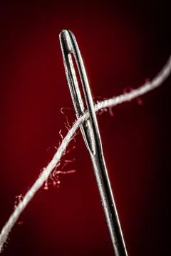 Needle with thread on a red background Stock Photos