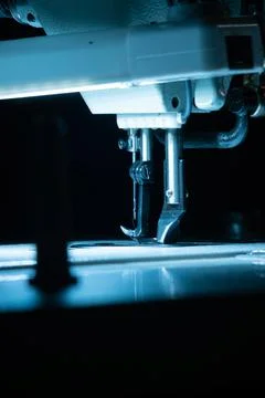 The needle with thread in the sewing machine is illuminated by cold backlight Foto stock