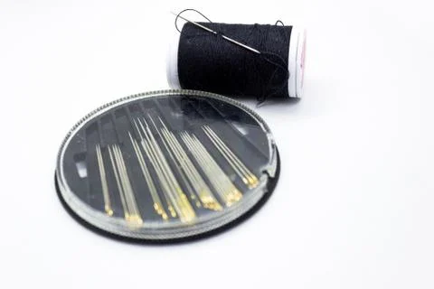 Needles and black thread for sewing against white background representing bet Stockfoto's