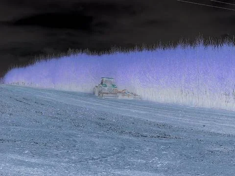Negative image - Tractor seeding a field beside a young tree alley in spring Stock Photos