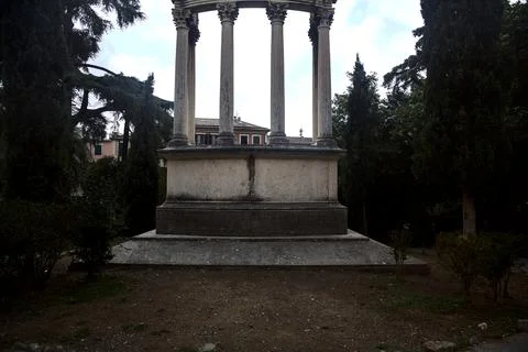 Neoclassic styled monument with two cypresses in a garden with the sky as bac Stock Photos