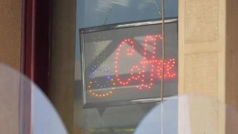 A neon coffee sign glows in the window of a caf in 4K slow motion 60fps Stock Footage 290099102