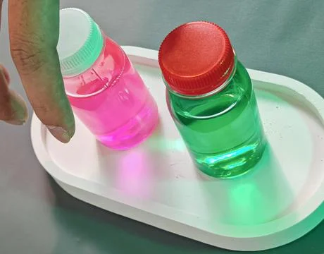 Neon Colored Liquid Bottles With Abstract Light Reflection On White Surface 写真素材
