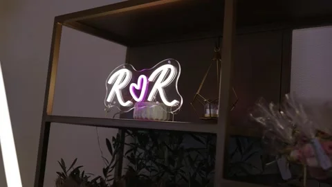 Neon initials with heart on shelf among wedding decor and gift details 動画素材 311903316