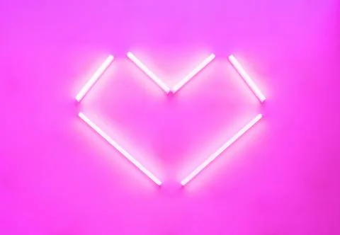 Neon lamps in the shape of a heart, angular shapes glowing on a pink backgrou Stock Photos