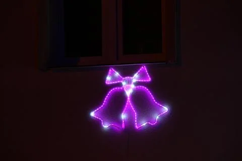 Neon light bow illuminated on wall near window, playful and decorative home.. Stock Photos