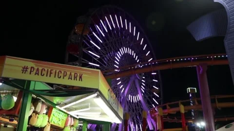 Neon light lit big ferris wheel ride in Pacific Park at Santa Monica beach Stock Footage 135797912
