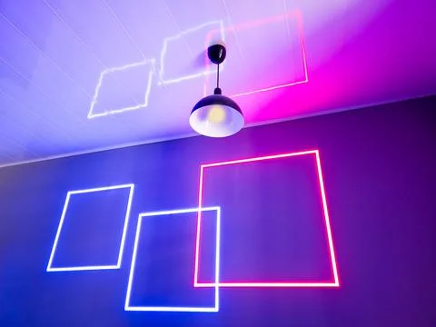 Neon light reflections create shapes on a ceiling in a room Foto stock