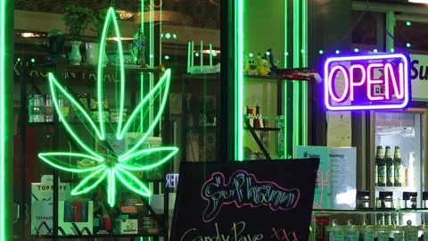 Neon light in shape of Cannabis leaf is seen in front of a weed shop. Stock Footage 278915305