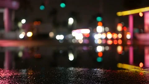 Neon lights reflection in puddle on road. Rain drops, wet asphalt of city street Stock Footage