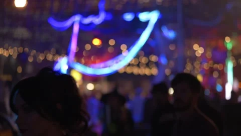 Neon lines glowing above crowd at night festival, bright colors and soft Video stock 321817448