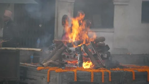 Nepal. Man putting a log into a cremation fire at Pashupatinath. 스톡 동영상 140291463