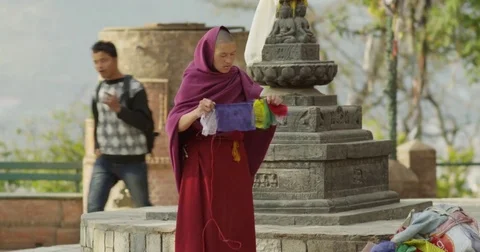 Nepali buddhist monk fixes prayer flags at Swayambhunath (Monkey Temple) Stupa. Stock Footage 72987194