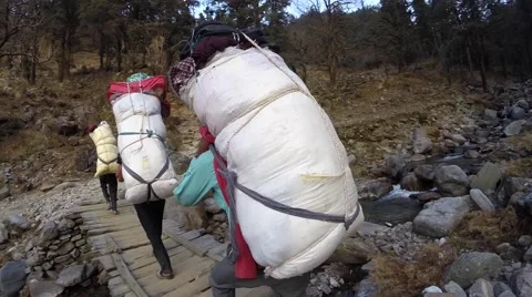 Nepali Porters trekking across stream Stock Footage 65770853