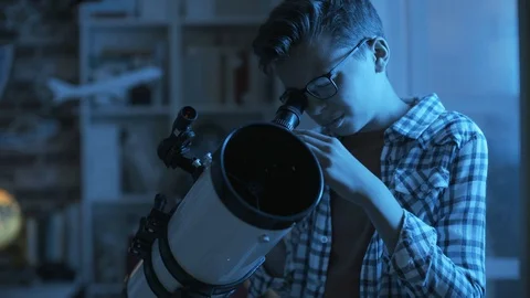 Nerd boy looking through a telescope and exploring constellations Stock Footage 128500824