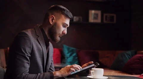 Nerd hipster guy sitting at bar table and using a tablet Stock Footage 57112940