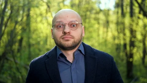 A nerd man adjusts his glasses, rolls his eyes and looks around suspiciously Stock Footage 192354217