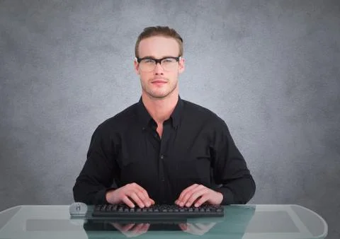 Nerd man at desk against grey wall with grunge overlay Stock Photos