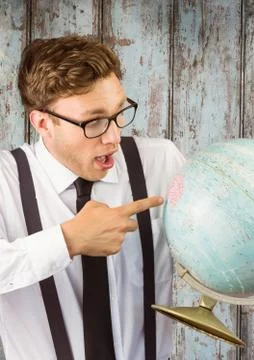 Nerd man pointing at globe against wood panel 스톡 사진