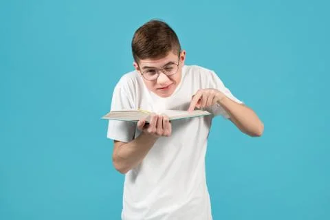 Nerd squeezing shoulders squinting one eye, pointing a finger at a book Stock Photos