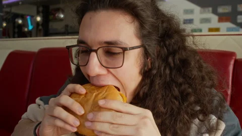 Nerdy Young Male Student Biting into Delicious Burger at Diner Stock Footage 335754310