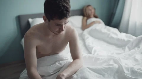 Nervous guy upset sitting on edge of bed because of problems with sex. Young Stock Footage 141566996