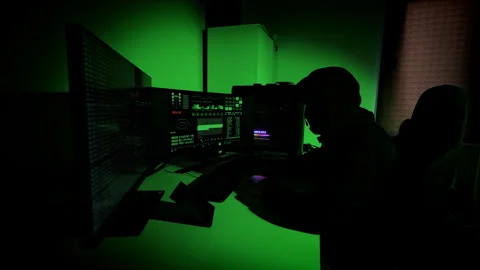 Nervous Hacker Checks Time and Anxiously Watches Code Screens in Green Light 動画素材 306283517