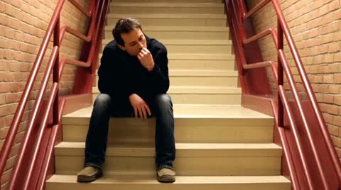 Nervous man chewing nails on steps Stock Footage 10713163