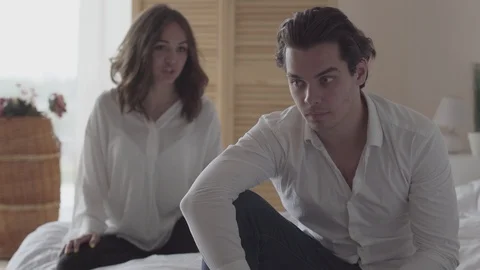 Nervous man sitting on the bed in the foreground while his wife shouting at him Stock Footage 112556737