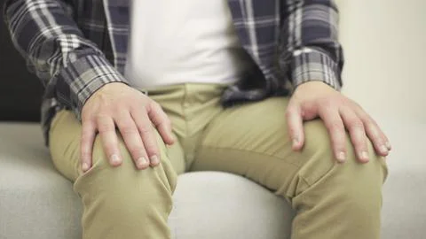 Nervous man sitting on sofa while making nervous hand gestures. Slow motion 스톡 사진