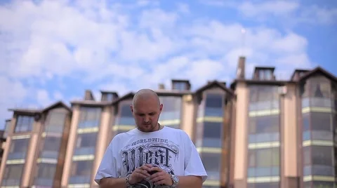 Nervous Man Stands Against the Backdrop of High-Rise Building and Sky and Stock Footage 66690126