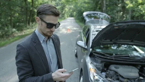 Nervous Young Man Talking on the Phone Near his Car Stock Footage