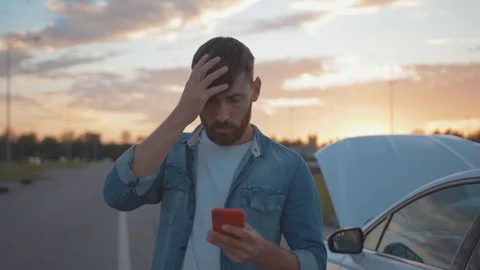 Nervous young man using smartphone calling car assistance services standing by Stock Footage 114253062