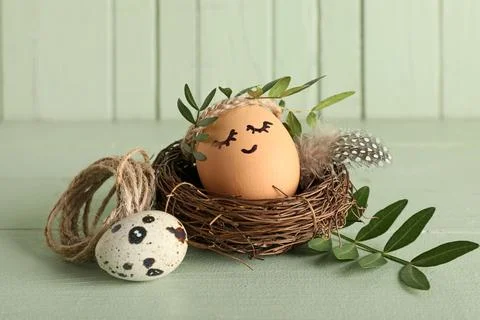 Nest of creative Easter eggs with leaves on green background Stock Photos