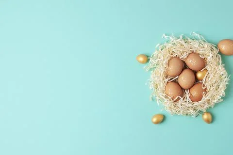 Nest with easter eggs with flowers on blue background. Flat lay, copy space Stock Photos