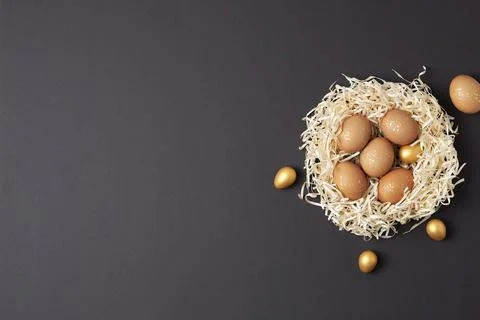 Nest with easter eggs with flowers on dark brown background. Flat lay, copy.. Stock Photos