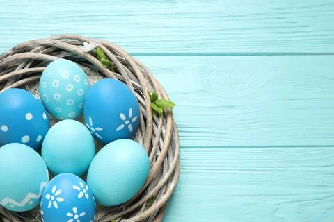 Nest with Easter eggs on light blue wooden background, top view. Space for te Foto stock